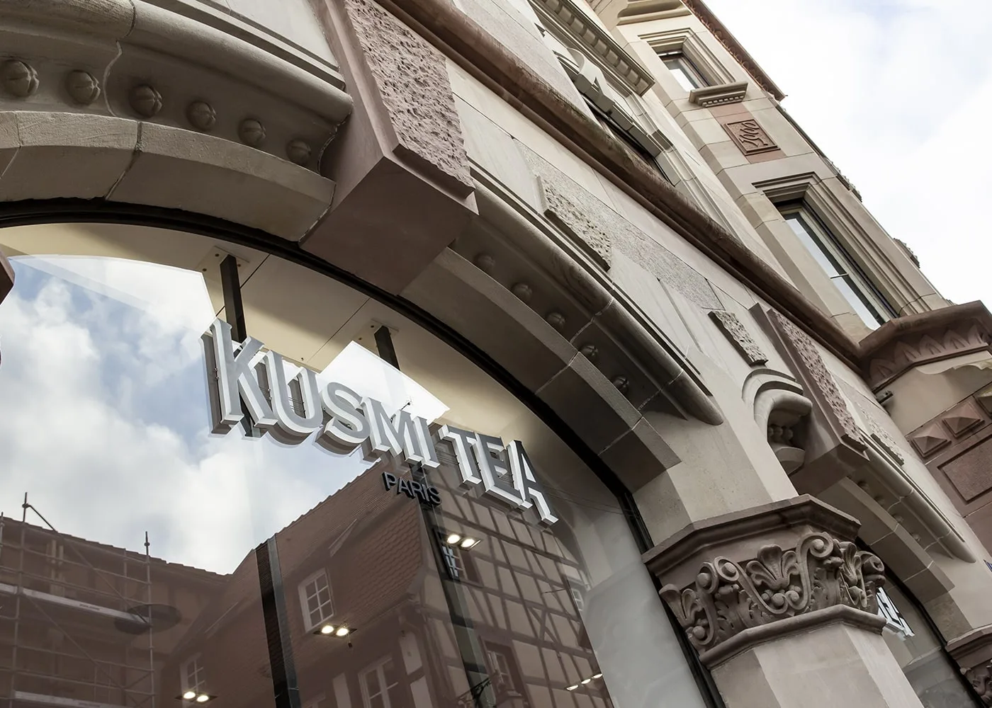 Façade en grès de la boutique Kusmi Tea à Colmar, enseigne en lettres blanches derrière la vitrine cintrée.